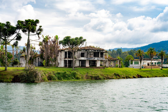 Ruins of Pablo Escobar&rsquo;s former lakeside mansion stand deteriorated and abandoned by the water in Guatape near Medellin, Colombia, surrounded by tropical trees and natural landscape
