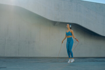 Jumping rope while enjoying outdoor fitness at a modern urban location in bright daylight
