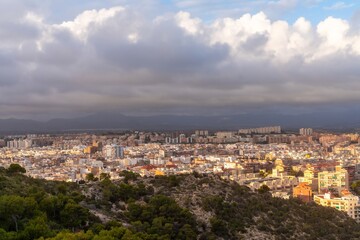 Obraz premium Bright hilltop cityscape with sea. Vivid golden sunlight bathes small city on hill surrounded by lush greenery and distant sea