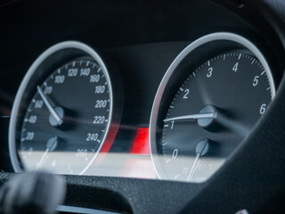 Close view of car dashboard with speedometer and tachometer gauges. Automotive interior for vehicle speed, engine RPM display.