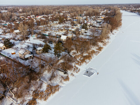 Aerial view of snow-covered houses near frozen river in Uralsk, Kazakhstan, during winter. c.