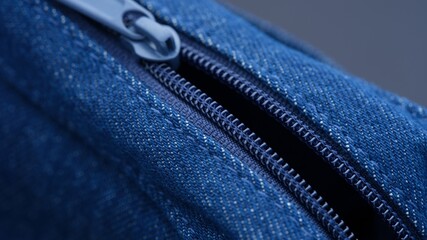 Close-up shot of an open zip on a blue denim bag.