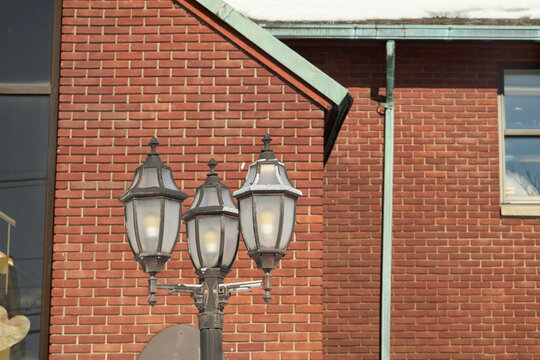 Traditional streetlamp in front of brick building with copper gutters
