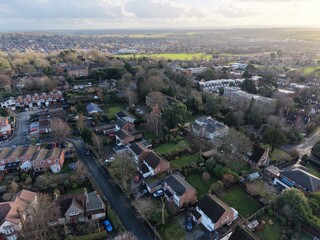 High‑resolution drone image showing rows of homes, green fields and distant hills under bright daylight in Wirral, Merseyside. Ideal for illustrating suburban development and the blend of rural and ur
