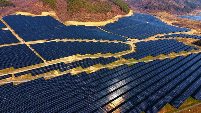 Geometric rows of solar panels in large power plant. High angle view showing the systematic arrangement of photovoltaic panels in a rural energy facility.