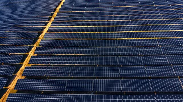 Top down aerial shot of solar panel patterns. Directly overhead view of numerous solar panels forming a geometric blue pattern on the ground.