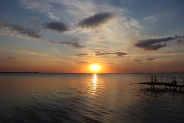 Obraz premium Peaceful lake sunset with pier and warm evening sky