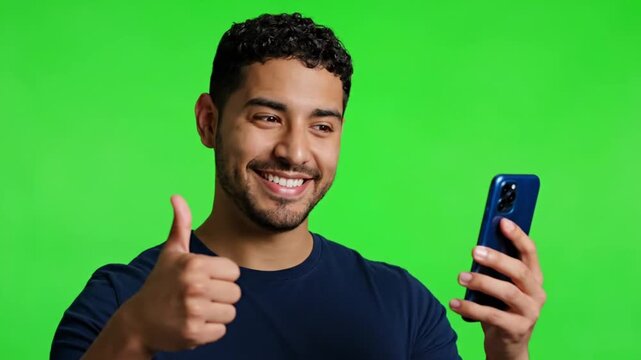 Young man intensely focused on his smartphone against green background