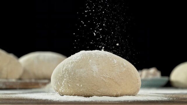 The dough on the kitchen table with falling flour . Filmed on a high-speed cinema camera at 1000 fps
