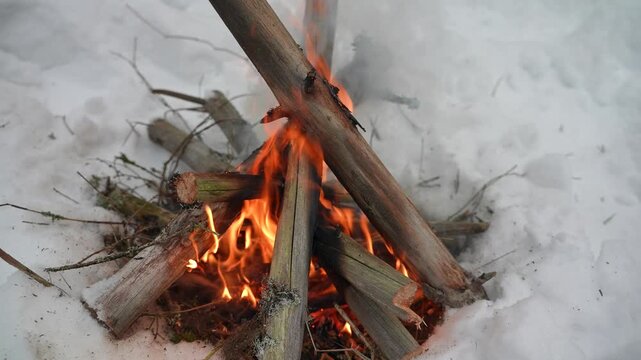 A hiking campsite in a winter forest, with a campfire burning on the snow. A snowy overnight stop with a fire. Winter camping.