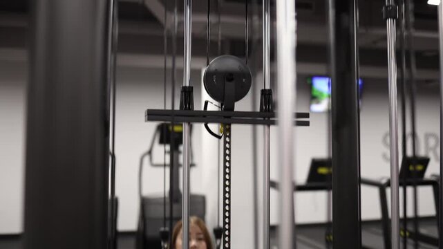 Young woman performs lat pulldown exercise on cable machine building upper body strength and muscle tone during focused workout in modern gym