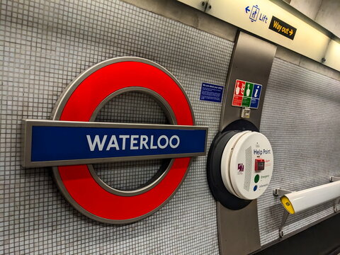 Iconic red and blue Waterloo station roundel sign on a tiled platform wall in the London Underground
