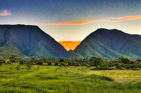 Sunrise with lush green field  over the west maui mountains. 
