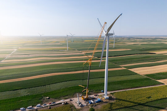 Wind turbine installation using a large construction crane. The assembly process of the turbine tower and rotor blades. Aerial view