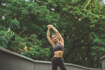 Happy fitness woman doing stretch exercise stretching her arms, female stretching for warming up before running or working out in the park outdoor.