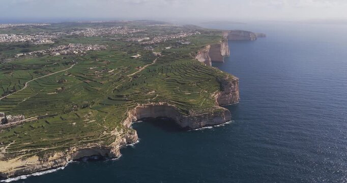Aerial view of the rugged coastline where the green fields meet the blue sea, a scenic contrast of nature's palette, Xlendi, Munxar, Malta.