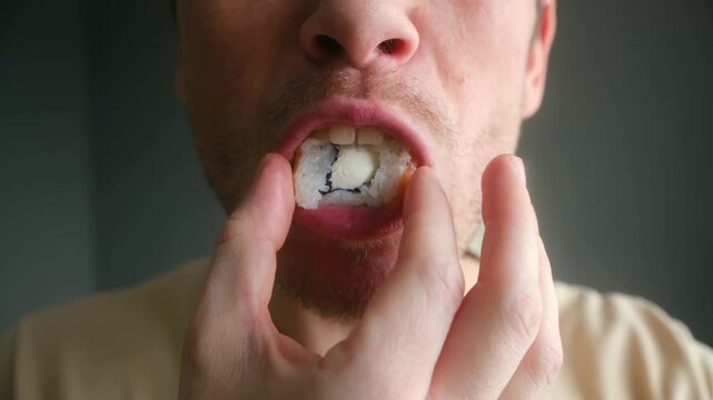 Caucasian man eating delicious japanese food with his hand. Close up capturing enjoyment tasting fresh sushi roll, showcasing appetite, savoring moment. Man eating sushi roll close up with pleasure