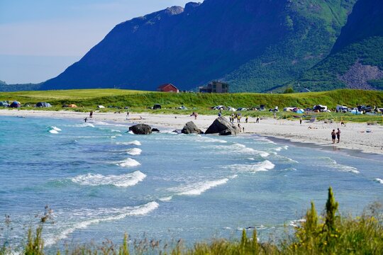 Tourists enjoy the crystal clear waters at Skagsanden beach in Lofoten, Norway.