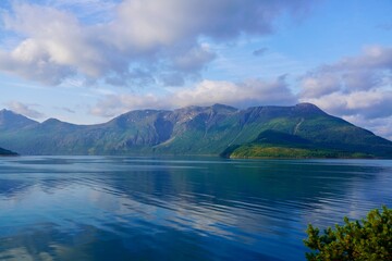 Obraz premium White clouds drift above a dramatic landscape of mountains and fjord in Helgeland, Norway.