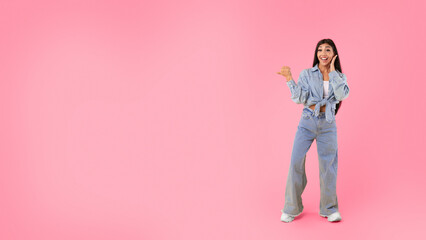 Wow, Special Offer. Excited young woman pointing finger aside at free copy space standing isolated over yellow orange studio background, full body length. Positive female showing place for ad, banner © Prostock-studio