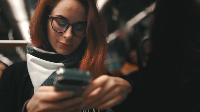 Woman with glasses using smartphone in subway train