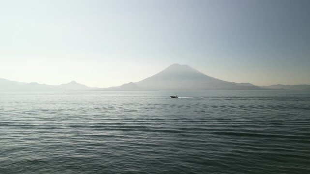 Aerial pan on boat on Lake Atitlan in morning light with volcano view