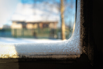 Frost on the inside of a window in winter, showing a frozen house with delicate ice crystals covering  glass. Beautiful yet concerning natural pattern indicating extreme cold and poor insulation.