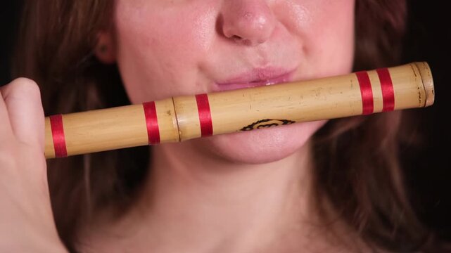 Woman playing traditional bamboo flute. Close up of female musician performing Indian classical music with bansuri. Cultural instrument concept.