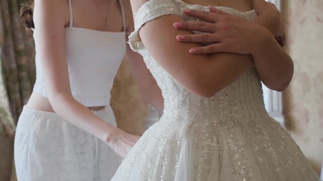 A beautiful young bride's mother ties her wedding dress, close-up