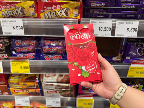 Person Holding Delfi Red Chocolate Gift Box with Heart and Rose Design in a Grocery Store