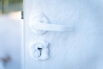 Frozen door handle and lock covered in frost during severe winter conditions. Close-up view of ice-covered door  house freezing from inside cold weather home insulation problems and climate challenges
