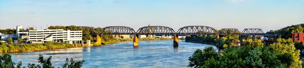 Obraz premium Union Pacific Missouri River Bridge in Omaha Nebraska. Historic steel truss railroad bridge crosses the water near a parking garage at sunset