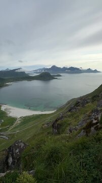 Cinematic panoramic footage of the stunning Haukland Beach coastline with turquoise sea, white sand, and dramatic mountain peaks in Lofoten, Norway