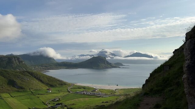 Cinematic panoramic footage of the stunning Haukland Beach coastline with turquoise sea, white sand, and dramatic mountain peaks in Lofoten, Norway