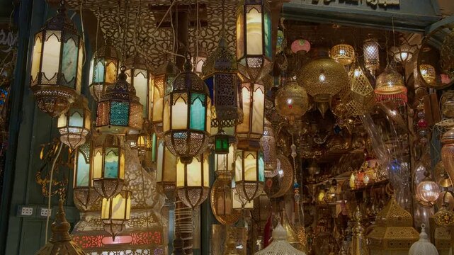 Glowing arabic lamps for sale swinging in the wind in front of egyptian souvenir shop. Traditional middle eastern lanterns. Holy month of Ramadan at Khan El Khalili market, Cairo, Egypt