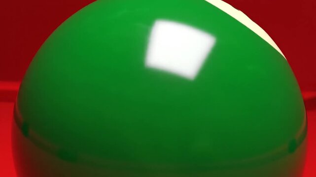 Close-up of a vibrant green snooker ball on a red felt table, ready for play.