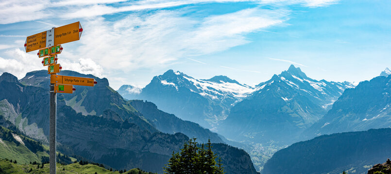 Hiking signs at the Schynige Platte, iconic mountains Eiger and Moench in the background