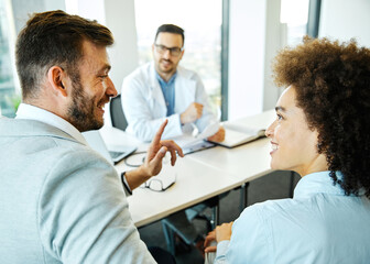 Young doctor and young couple talking in office in the clinic or hospital. Marriage and...