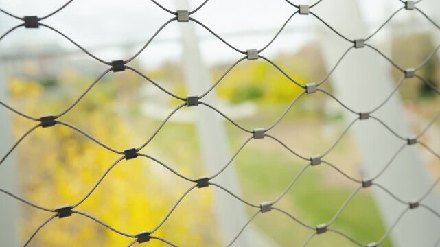 Metal wire mesh fence with blurred city background. Abstract industrial pattern 