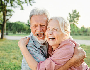 Happy active senior couple having fun talking and hugging in park outdoors