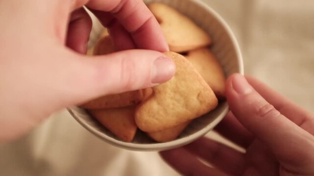 Close-up of heart-shaped butter cookies in a white ceramic bowl. Baked treats on a bright and warm minimalist background. Perfect for romantic holiday baking or Mother&rsquo;s Day, Valentine's Day.