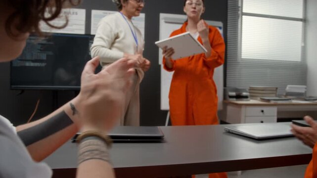 Candid shot of graduation ceremony in prison education program with focus flowing from young woman as female inmate accepting certificate to group of people applauding