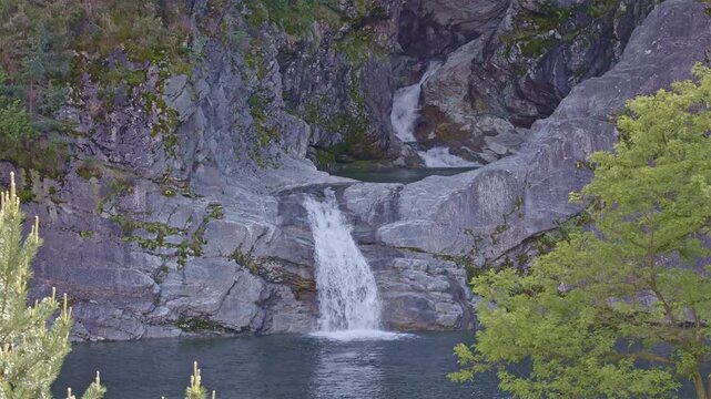 A scenic waterfall tumbling through a steep, wooded gorge. Cascata della Boggia waterfall, Lombardy, Italy.