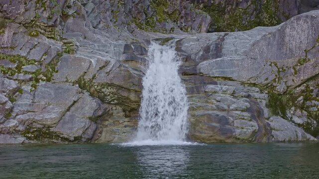 A scenic waterfall tumbling through a steep, wooded gorge. Cascata della Boggia waterfall, Lombardy, Italy.