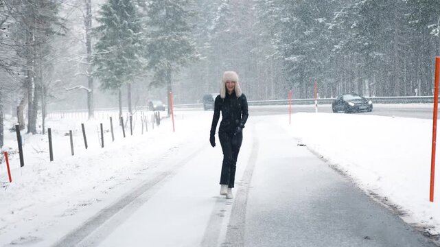 Portrait young adult mid age smile woman enjoy have fun walking in park forest snowfall cold winter day. Female portrait person happiness wear black ski overall stylish fur hat snowflakes background