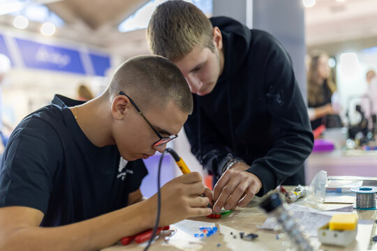 Young men learning electronics soldering skills in workshop