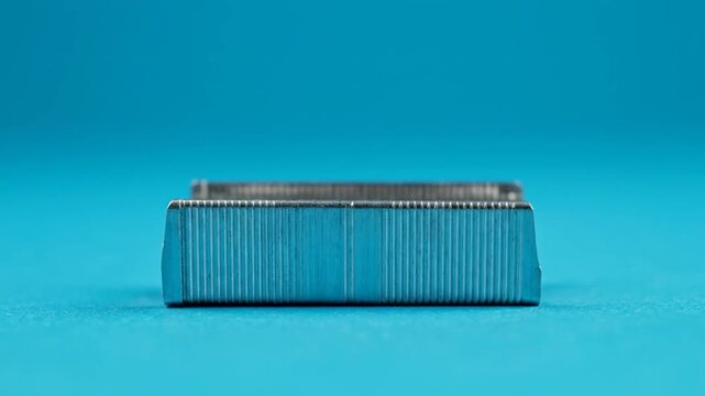 Close-up of a stack of staples on a vibrant blue background, ready for office use.
