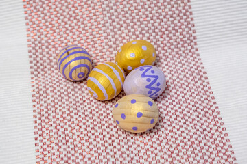 Fototapeta premium Hand-Painted Easter Eggs In Yellow And Purple Decorative Spring Crafts On Woven Cloth