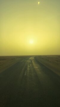 Drive on curved asphalt road through Sahara Desert dry lake Chott El Djerid with sunrise in golden light, vertical video