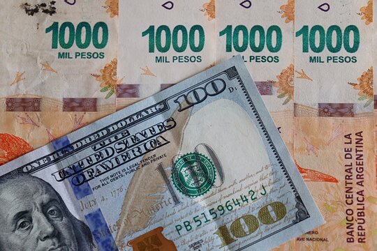 Argentine 1000 Pesos banknotes next to a 100 US dollar bill. Concept of exchange rate and  inflation in Argentina. Pesos Argentinos. 